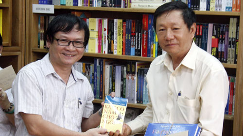 Nhà văn Nguyễn Nhật Ánh (trái) tặng tập truyện Bàn có năm chỗ ngồi cho thầy giáo Diệp Vĩ Cường - hiệu trưởng Trường THCS Bình Tây- Ảnh: L.Điền